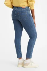 Jean de corte skinny y tiro alto, confeccionado en denim azul con lavado medio. Presenta diseño clásico de cinco bolsillos y cierre frontal con botón y cremallera.