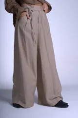 Pantalón negro de corte sastrero con tablas frontales y cintura con lazo. Diseño de pierna ancha y tiro alto.