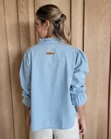 Blusa de algodón con cuello mao y volados, mangas largas con puños elásticos y corte holgado.