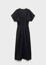 Vestido largo de color negro con cuello en pico y mangas cortas. Presenta un panel fruncido en la cintura que define la silueta y un diseño recto. Confeccionado en una mezcla de lino y ramio con forro de algodón.