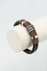 Pulsera marrón de cuero trenzado con detalles metálicos plateados.