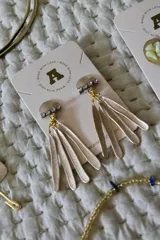 Aros colgantes dorados con base circular con incrustaciones de strass y flecos de metal.