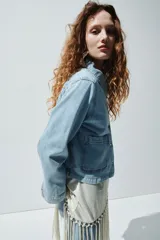 Campera corta en denim de algodón con cuello, cierre de botones y canesú en la espalda. Modelo ajustado con bolsillos parche adelante y puños abotonados.