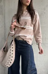 Sweater de punto con rayas horizontales blancas y base en tono beige y rosado, cuello polo con botones y mangas largas.