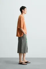 Camiseta boxy fit de punto tejido en hilatura de algodón, color terracota, con cuello redondo y manga corta. Estampado frontal de dados en tonos grises y blancos dentro de un óvalo.