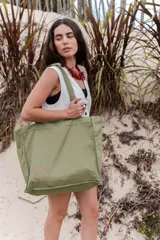 Bolso tipo tote de tela color verde oliva, con dos bolsillos frontales y cierre superior.