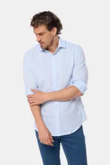Camisa de manga larga, corte slim fit, color celeste con finas rayas verticales blancas. Presenta cuello camisero y un pequeño logo bordado en el pecho.