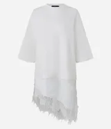 Remera de algodón corte oversized, color blanco, con cuello redondo, mangas cortas amplias y ruedo asimétrico con detalle de encaje aplicado.