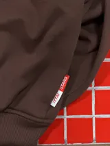 Hoodie de color marrón oscuro con capucha y estampado tipográfico en color blanco en la parte posterior.