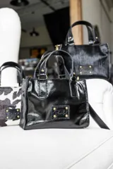 Mini bag negra de cuero charol con doble asa corta y detalles de costuras en color tostado.