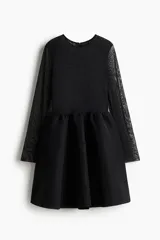 Vestido corto de malla transparente con detalles de strass tono sobre tono. Presenta mangas largas, cuerpo ajustado, escote redondo y cierre oculto en la espalda. Incluye costura fruncida en la cintura y falda con vuelo, con forro parcial.