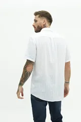 Camisa de manga corta confeccionada en lino y algodón, con fit regular y logo bordado. Color beige con rayas verticales blancas.