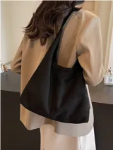 Bolso tipo hobo de material tipo gamuza o nobuk, color marrón camel. Presenta un diseño de silueta suave y caída, con una correa de hombro delgada de cuero liso del mismo tono.