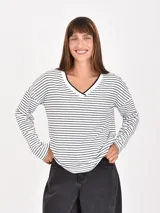 Remera de manga larga con estampado de rayas horizontales blancas y negras, cuello en V con ribete negro.