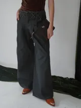 Sobre tipo cartuchera de lona con estampado de camuflaje y terminaciones en cuero marrón.