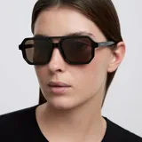 Lentes de sol con montura negra de diseño aviador contemporáneo, con doble puente estructural y lentes polarizadas en tono marrón.