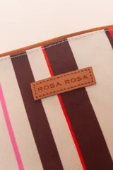 Sobre de algodón a rayas verticales de colores naranja, rosa, marrón, rojo y blanco. Tiene cierre superior con cremallera y tira de cuero marrón para la muñeca.