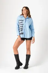 Camisa celeste de corte clásico con estampado de letras en negro en el frente.