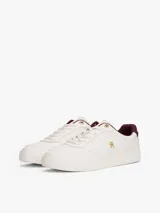 Zapatillas de cuero estilo tenis, color blanco, con cordones y suela de goma al tono. Presentan forro interior en color bordó, ojal superior metálico dorado y logo de monograma TH metálico en el lateral.
