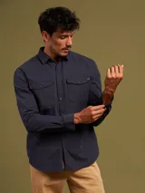 Camisa azul de manga larga con dos bolsillos frontales con botón.