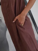 Vestido largo marrón de lino con detalle de cuero negro en la parte superior delantera y cartera trasera.