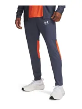 Pantalón deportivo Under Armour de la colección Challenger, color azul oscuro con detalles laterales en naranja. Presenta corte ajustado, cintura elástica con cordón, bolsillos laterales y cremalleras en los tobillos.