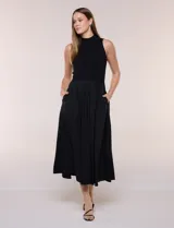 Vestido midi sin mangas de color verde militar, confeccionado con la parte superior en tejido de punto acanalado con cuello alto y falda acampanada de gran vuelo.