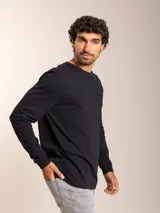 Remera blanca de manga larga con cuello redondo y logo bordado de un pájaro en el pecho.
