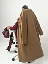 Tapado largo color camel confeccionado en lana escarada elastizada. Diseño clásico con cuello solapa y corte recto. Fabricado en Italia.