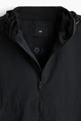 Campera rompevientos negra de nylon repelente al agua, con capucha ajustable, cierre frontal, bolsillos laterales y puños elásticos.