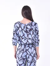 Blusa de mangas largas con estampado de hojas en tonos celeste y azul marino, con lazo en la cintura.