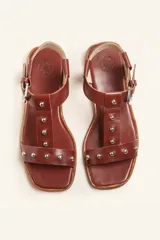 Sandalias negras de cuero con tiras finas, pulsera al tobillo con hebilla metálica y apliques de tachas plateadas.