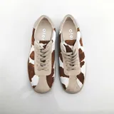 Championes de cuero con estampado de vaca en blanco y marrón, con cordones y suela de goma color beige.