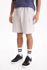 Bermuda cargo de felpa sin friza, color beige, con cintura elástica y bolsillos laterales con solapa.