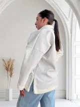 Buzo color crudo de ecocuero con cuello alto, cierre metálico dorado y puños con elástico.