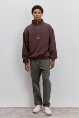 Buzo de cuello alto con cierre frontal parcial, de corte holgado y diseño minimalista con pequeño estampado central en el pecho.