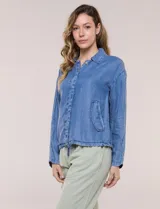 Camperita de denim liviano color azul, con cuello camisero, botones frontales ocultos, mangas largas de hombros caídos, bolsillos laterales y cordón ajustable en la cintura.