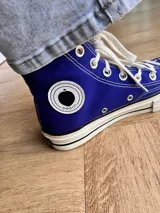 Zapatillas de lona color beige, tipo bota, con cordones marrones, puntera de goma y logo de peach engomado.