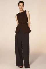 Pantalón de tiro medio con corte wide leg, presenta pliegues frontales, bolsillos laterales y trabilla con botón en la espalda. Cierre frontal con cremallera y botón.