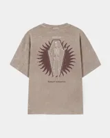 Remera oversize de color marrón topo con efecto acid wash, cuello redondo y manga corta. Cuenta con un pequeño estampado gráfico frontal con el texto 'WAKE UP IND' y una calavera.