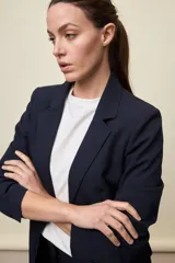 Blazer negro de líneas clásicas y silueta sastrera, con solapas y estructura definida.