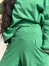 Pantalón tipo palazzo de tiro alto, confeccionado en jersey de algodón color verde. Presenta un diseño amplio con bolsillos laterales y una faja ancha en la cintura que proporciona ajuste y soporte.