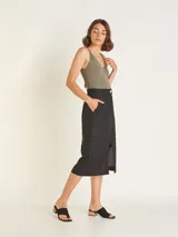 Falda midi color beige, de tiro alto con elástico en la cintura trasera, cierre y botón delantero. Tiene bolsillos delanteros y bolsillos cargo a los costados, con tajo en el delantero.