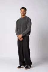 Sweater de tejido de punto grueso color tostado, con cuello redondo y mangas largas con puño elástico que incluye una etiqueta decorativa.