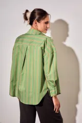 Camisa de corte oversize con estampado de rayas verticales en tonos verde, blanco y ocre. Presenta cuello clásico, cierre frontal con botones, bolsillo en el pecho y mangas largas con puños abotonados.