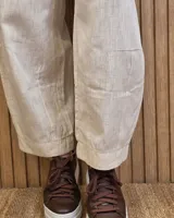 Pantalón de lino color marrón con corte barrel, tiro medio, cintura elástica con cordón de ajuste y bolsillos laterales.