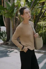 Bolso tipo shopper de hombro en color beige, con diseño estructurado, doble asa y detalle de pespuntes verticales en el cuerpo. Incluye un colgante decorativo tipo etiqueta y cierre imantado.
