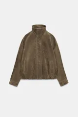 Chaqueta de ante con cuello subido, manga larga y bajo abullonado con elástico. Presenta cierre frontal con cremallera y botones a presión ocultos, además de bolsillos laterales de vivo.