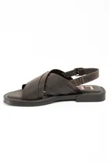 Sandalias de cuero marrón oscuro, con tiras cruzadas en el empeine, hebilla metálica grande decorativa y tira ajustable en el talón con hebilla plateada.