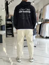 Canguro oversize color beige, con capucha y amplio estampado tipográfico en la espalda.